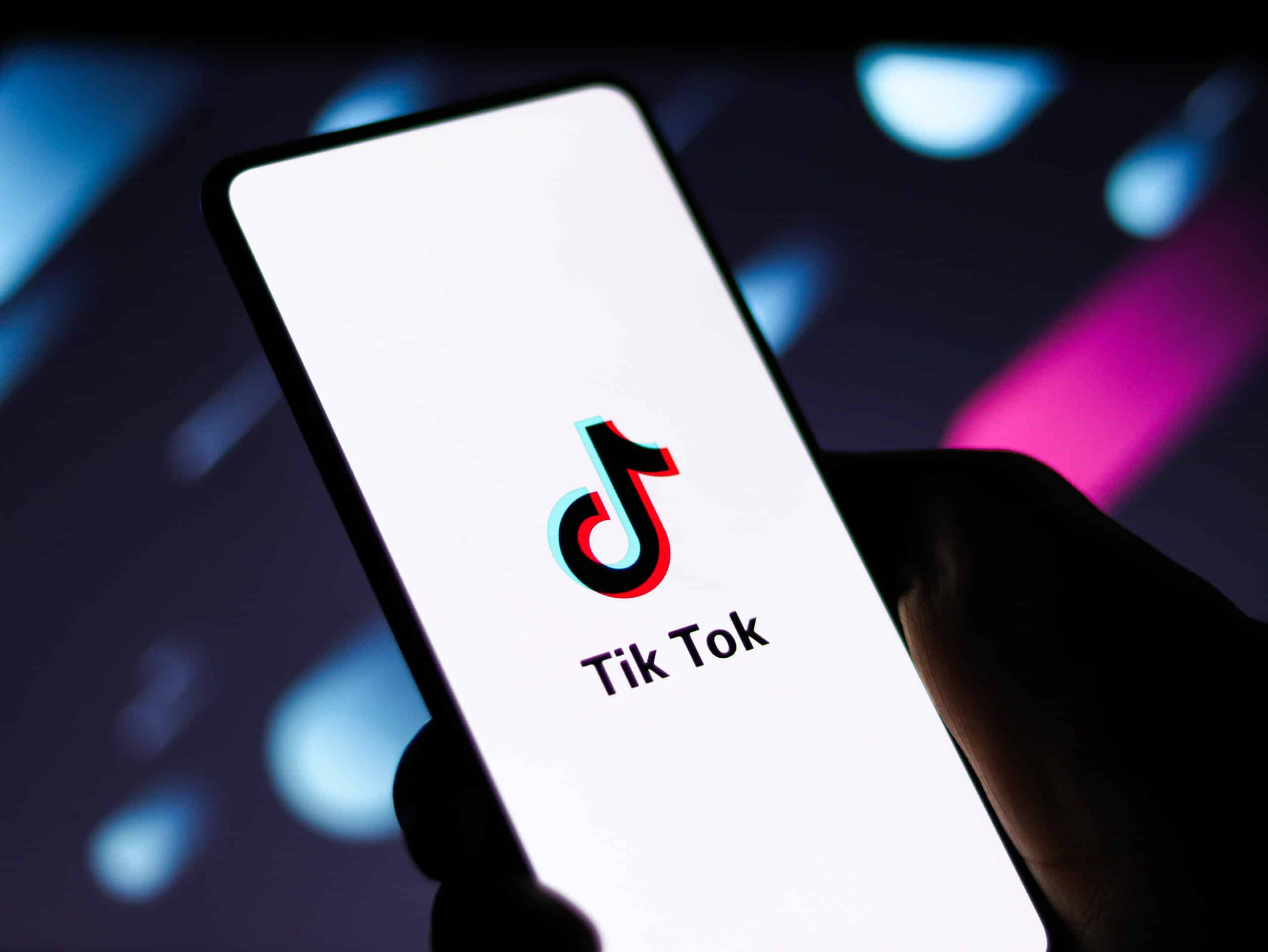 Osoba trzyma telefon z logo TikTok, przedstawiającym strategię marketingową.